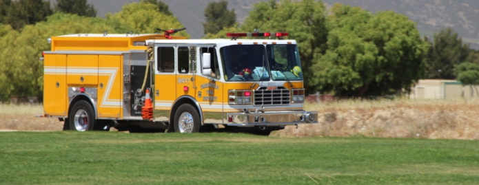 A yellow fire truck in a field.
